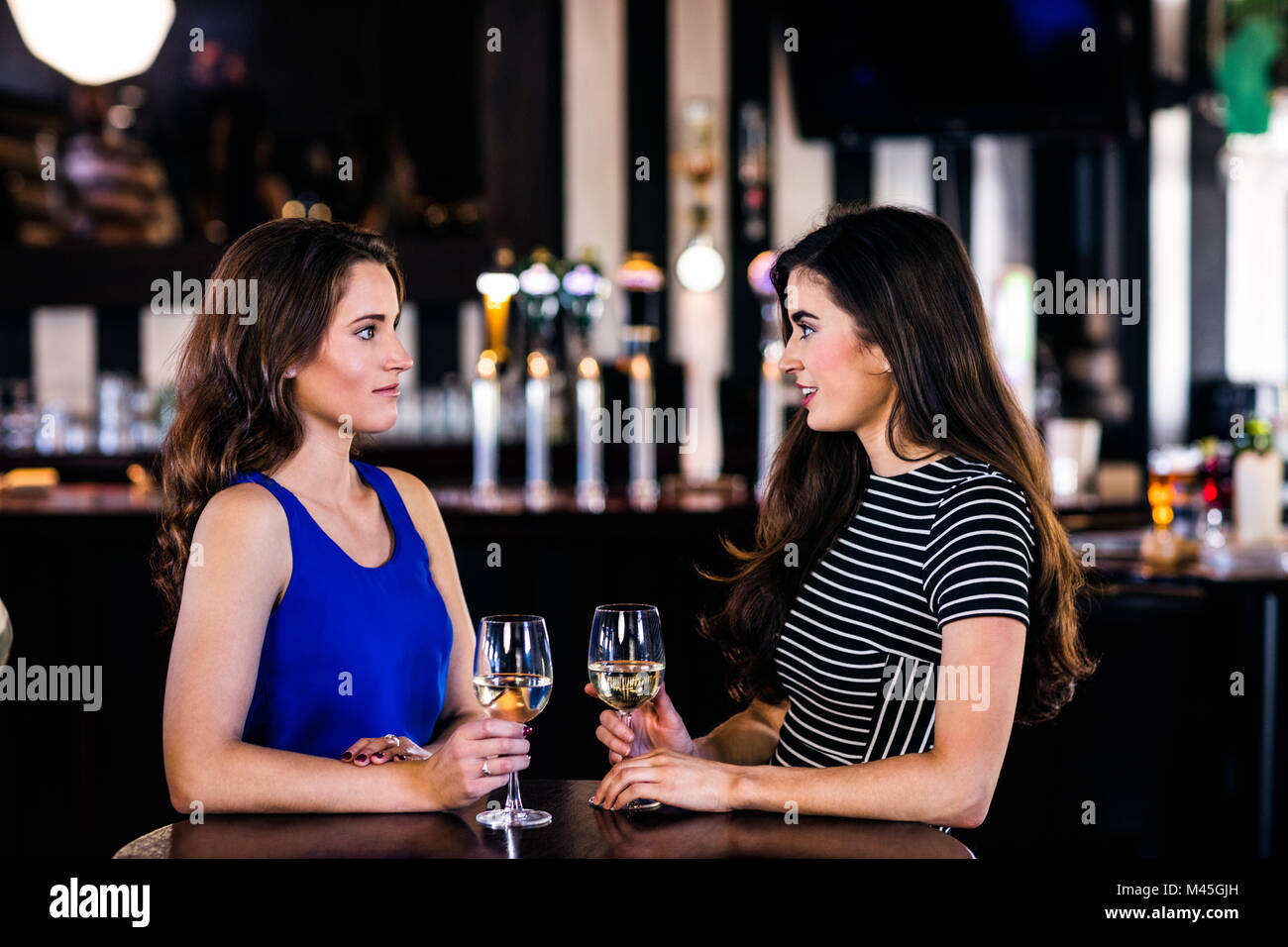 Brunettes talking and holding glasses of white wine Stock Photo