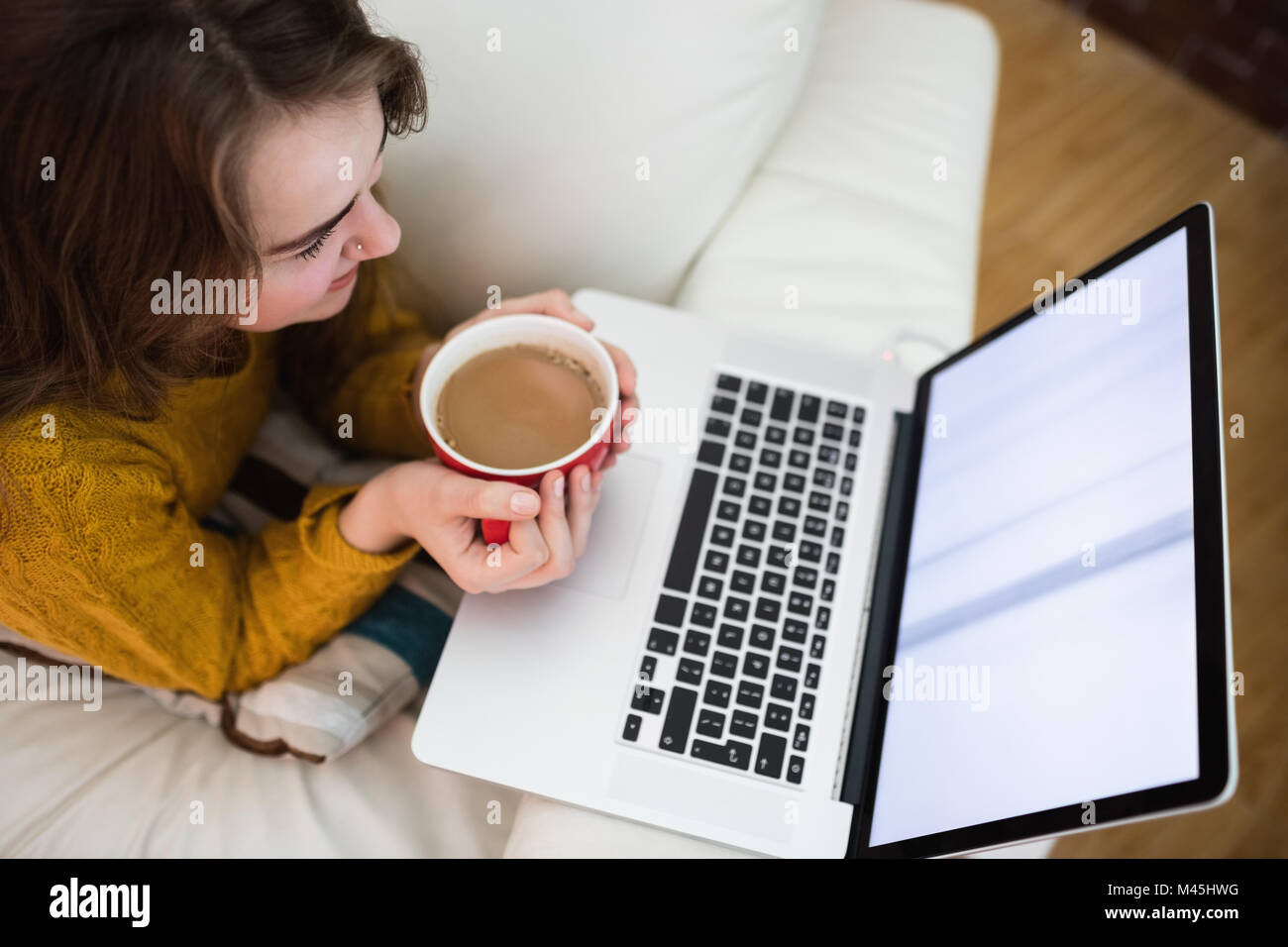 Smiling pretty woman using laptop while drinking coffee Stock Photo