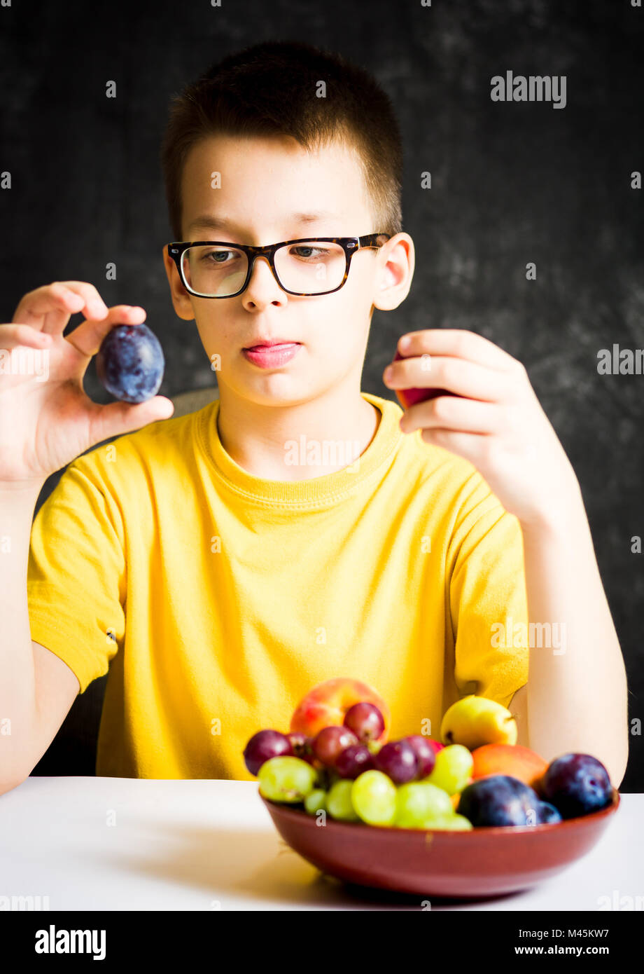 Teenage boy choosing between two kind of fruits Stock Photo