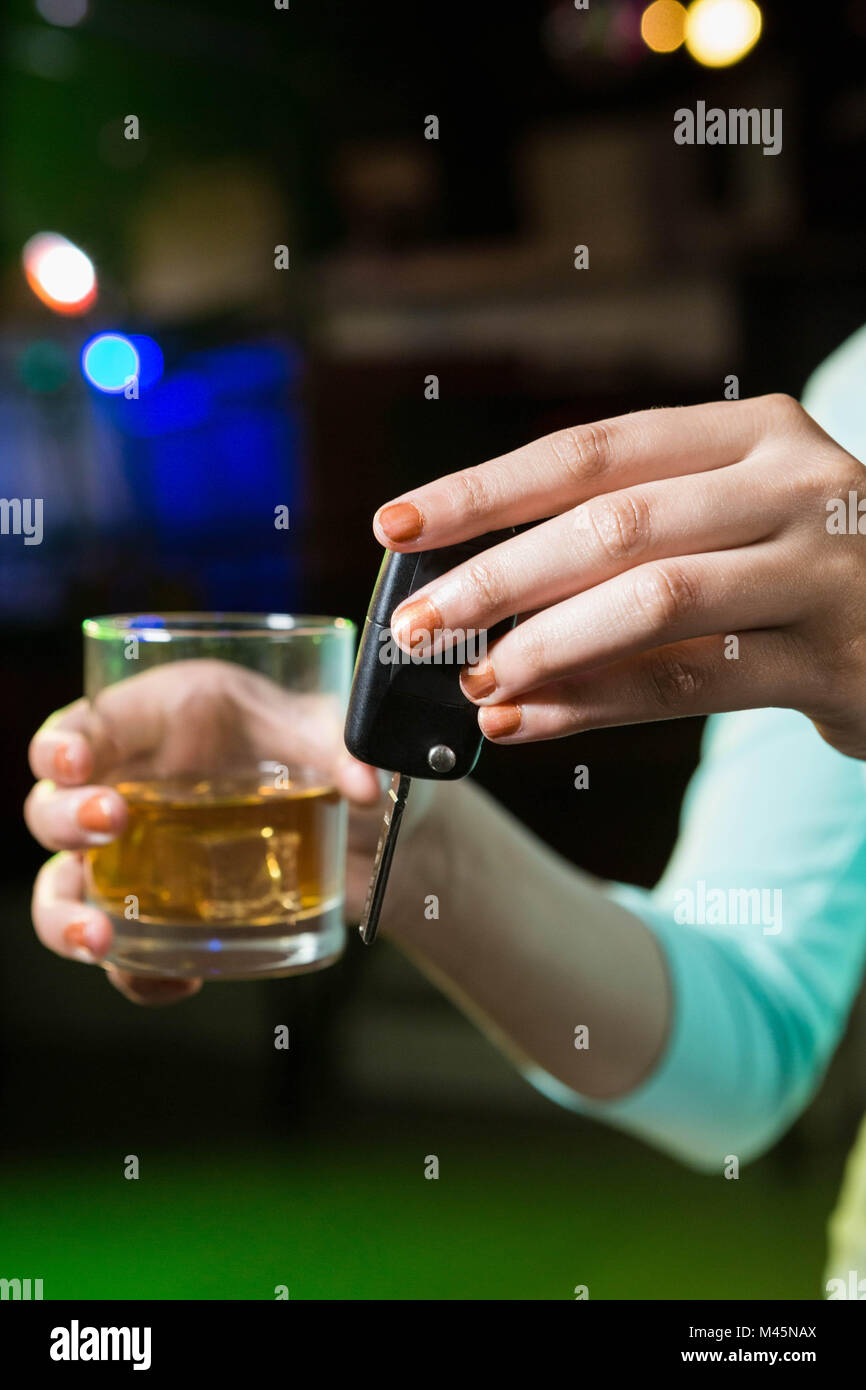 Woman holding a glass of whiskey and car keys Stock Photo