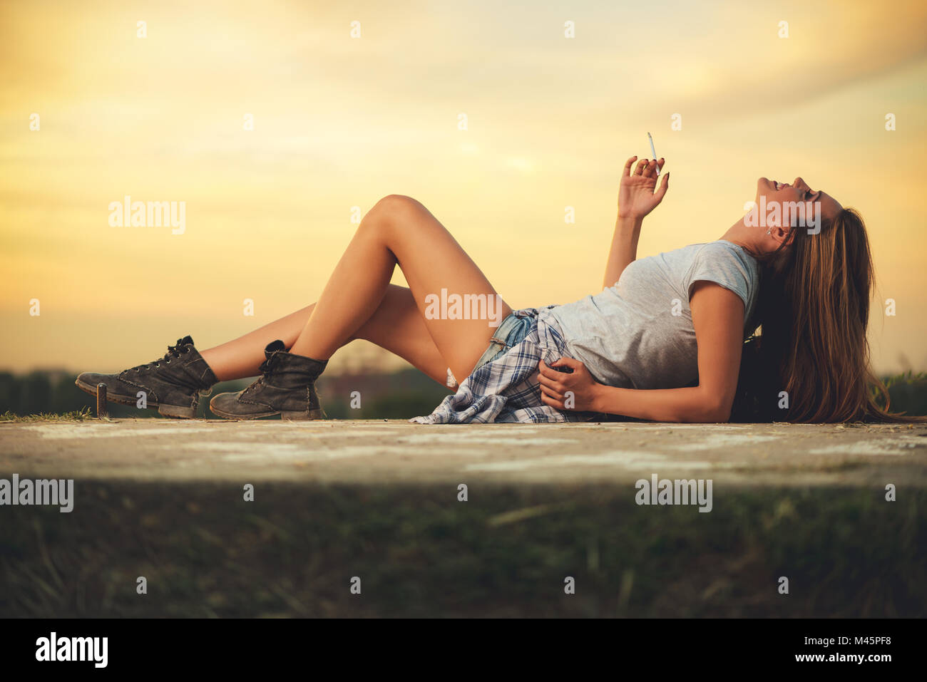 Beautiful imagined young woman lying down at sunset background and