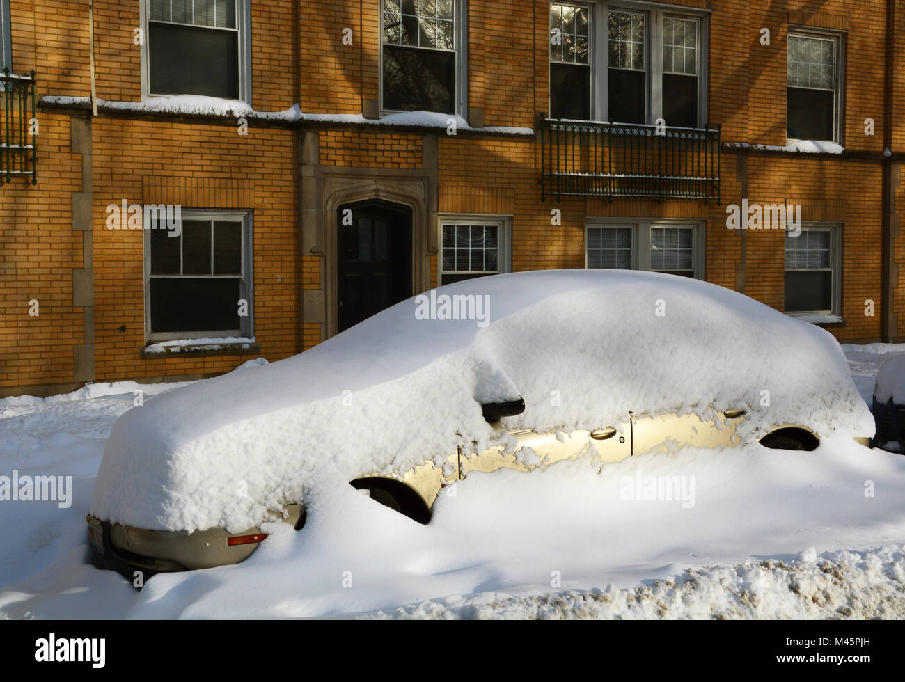 A car is buried in the snow on a residential side street after a series of snow storms in Chicago. Stock Photo