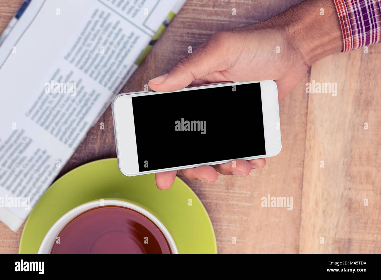 Man using smart phone by coffee and newspaper on table Stock Photo