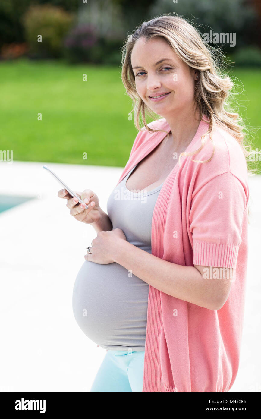 Pregnant woman touching her belly and texting Stock Photo