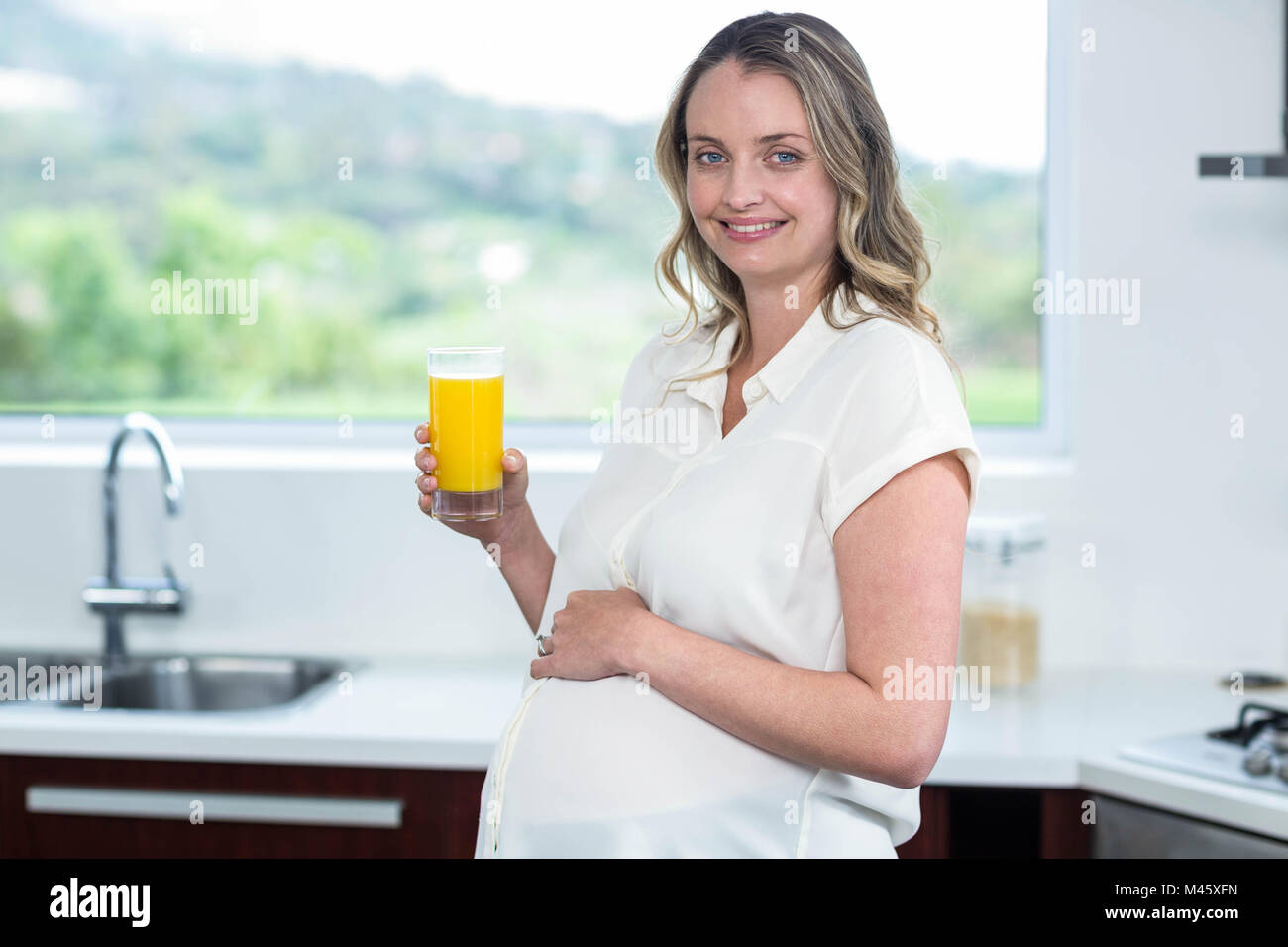Pregnant woman drinking a glass of orange juice Stock Photo - Alamy