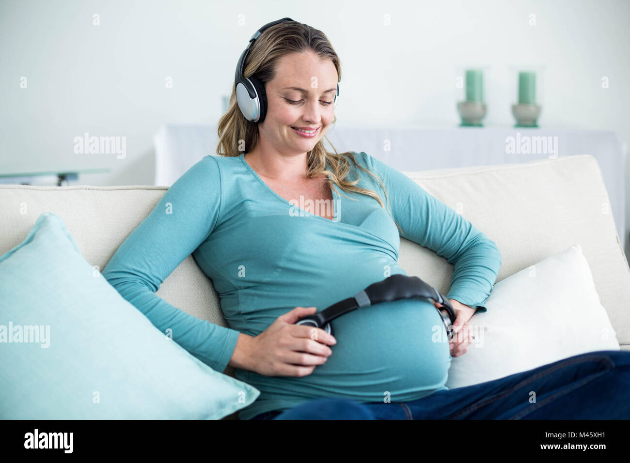 Pregnant woman listening to music with headphones on belly Stock Photo ...