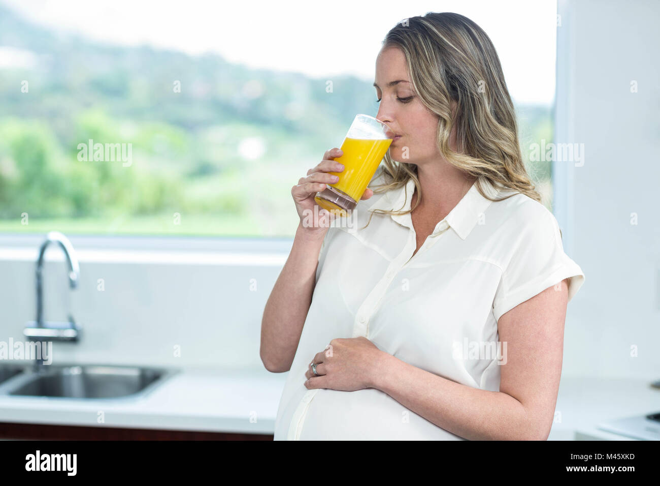 Pregnant woman drinking a glass of orange juice Stock Photo - Alamy