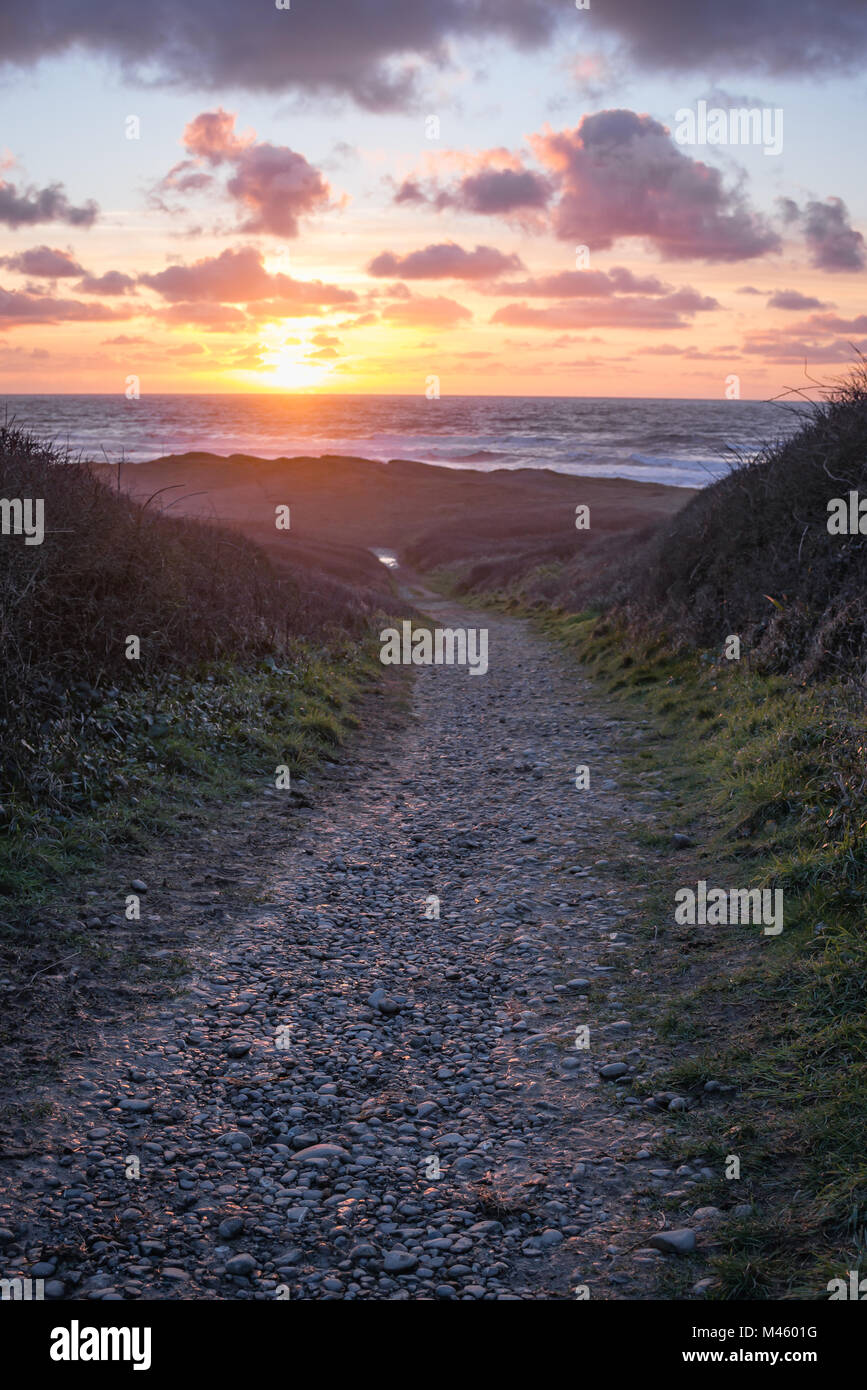 Gravel path leading down to Widemouth Bay at sunset. Stock Photo