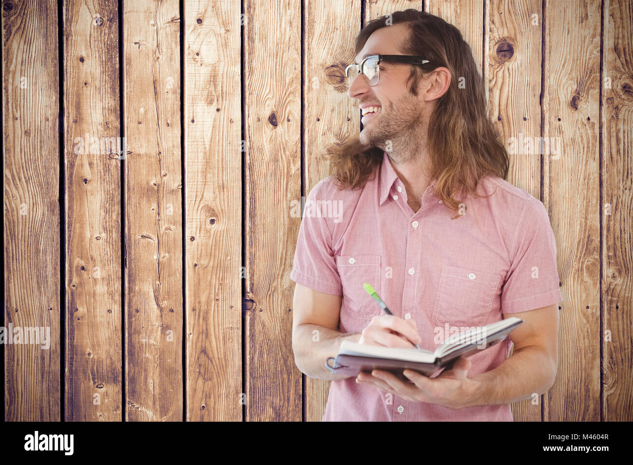Composite image of happy hipster holding book and pen Stock Photo