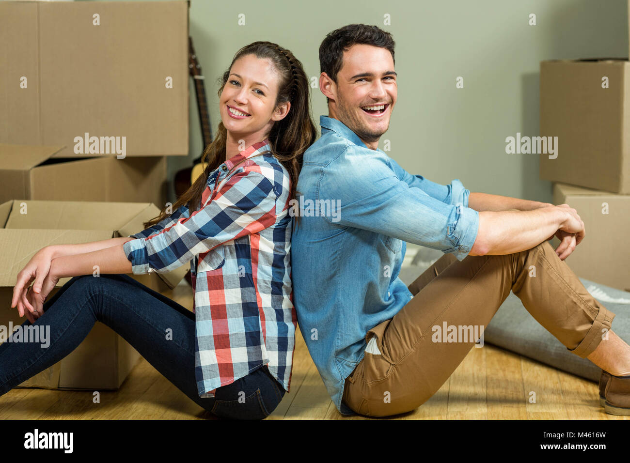 Young couple sitting back to back in their house Stock Photo