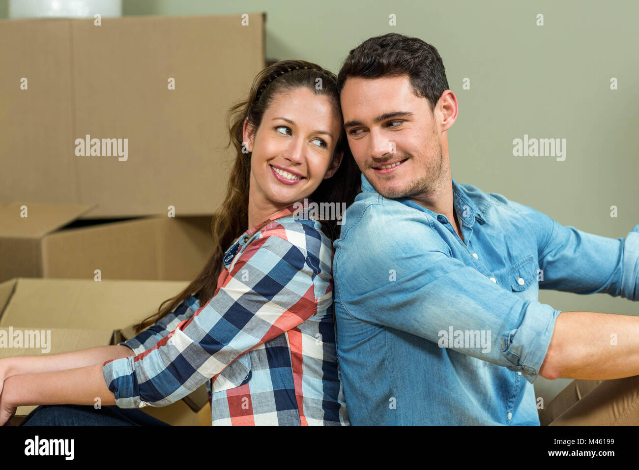 Young couple sitting back to back in their new house Stock Photo