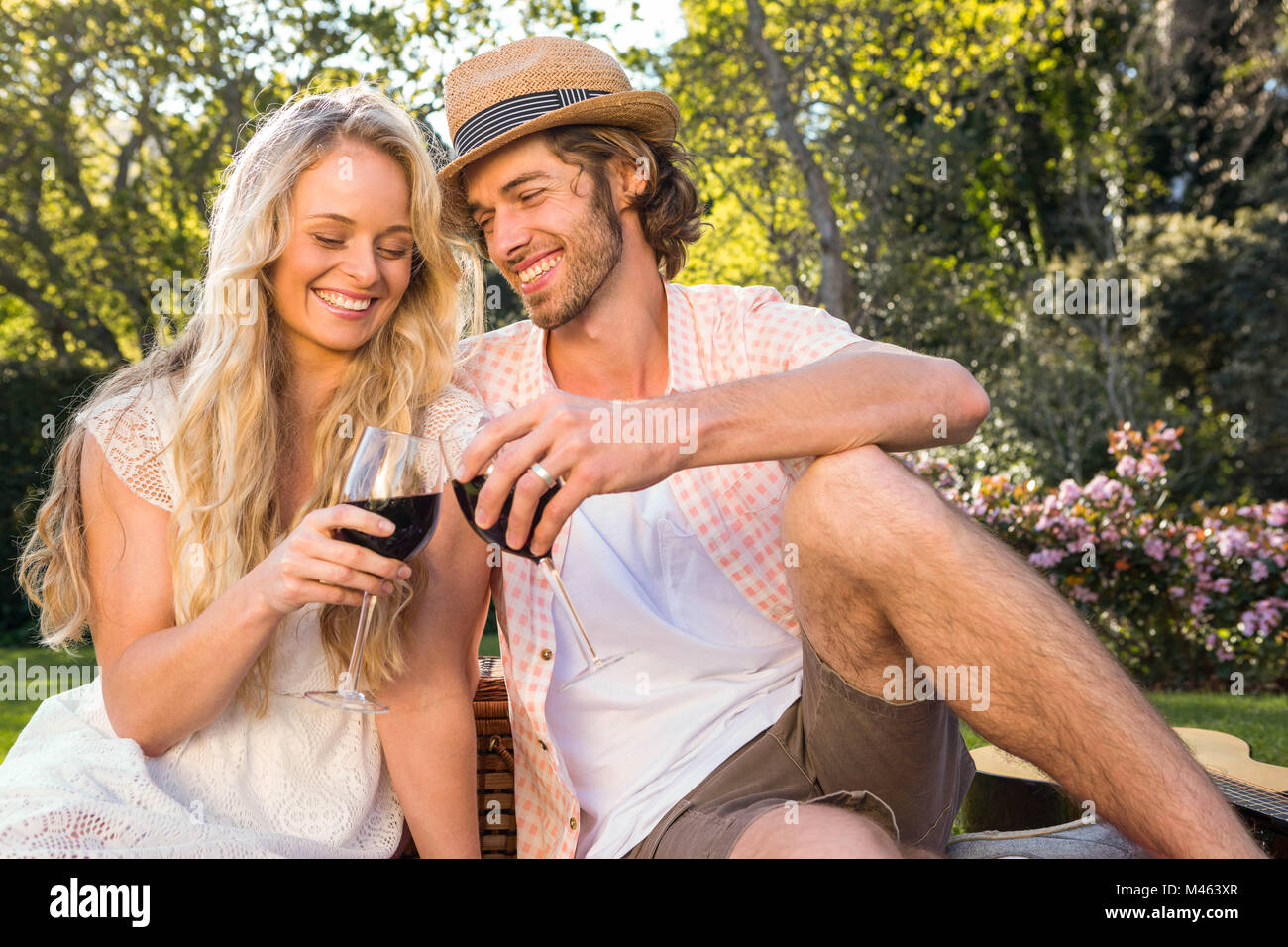 Happy couple having a picnic and drink red wine Stock Photo - Alamy