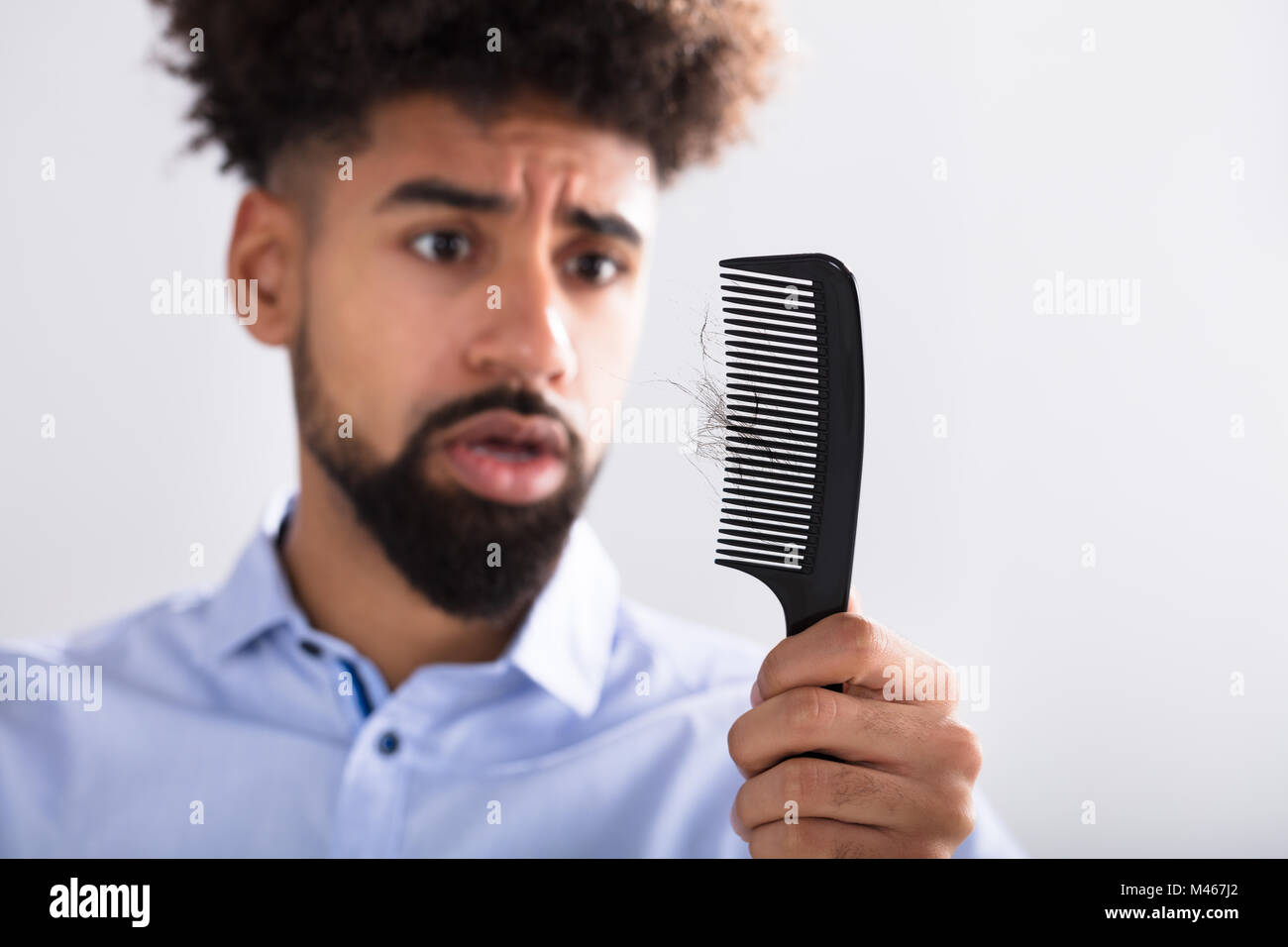 Young Man Holding Comb Looking At Hair Loss Stock Photo
