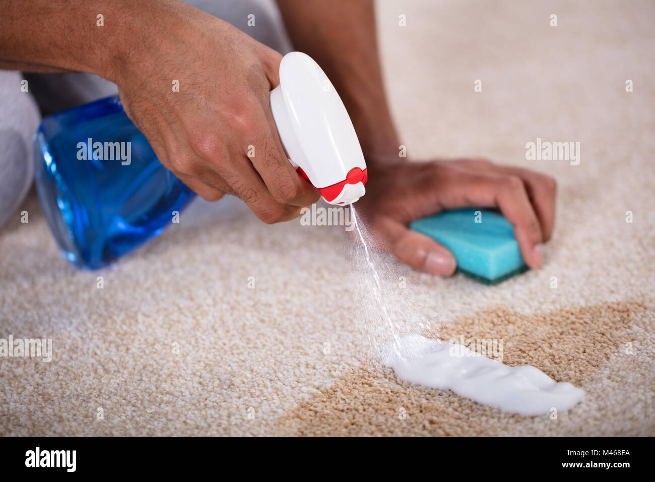 Janitor Cleaning Spilled Coffee On Carpet With Spray Bottle Stock Photo