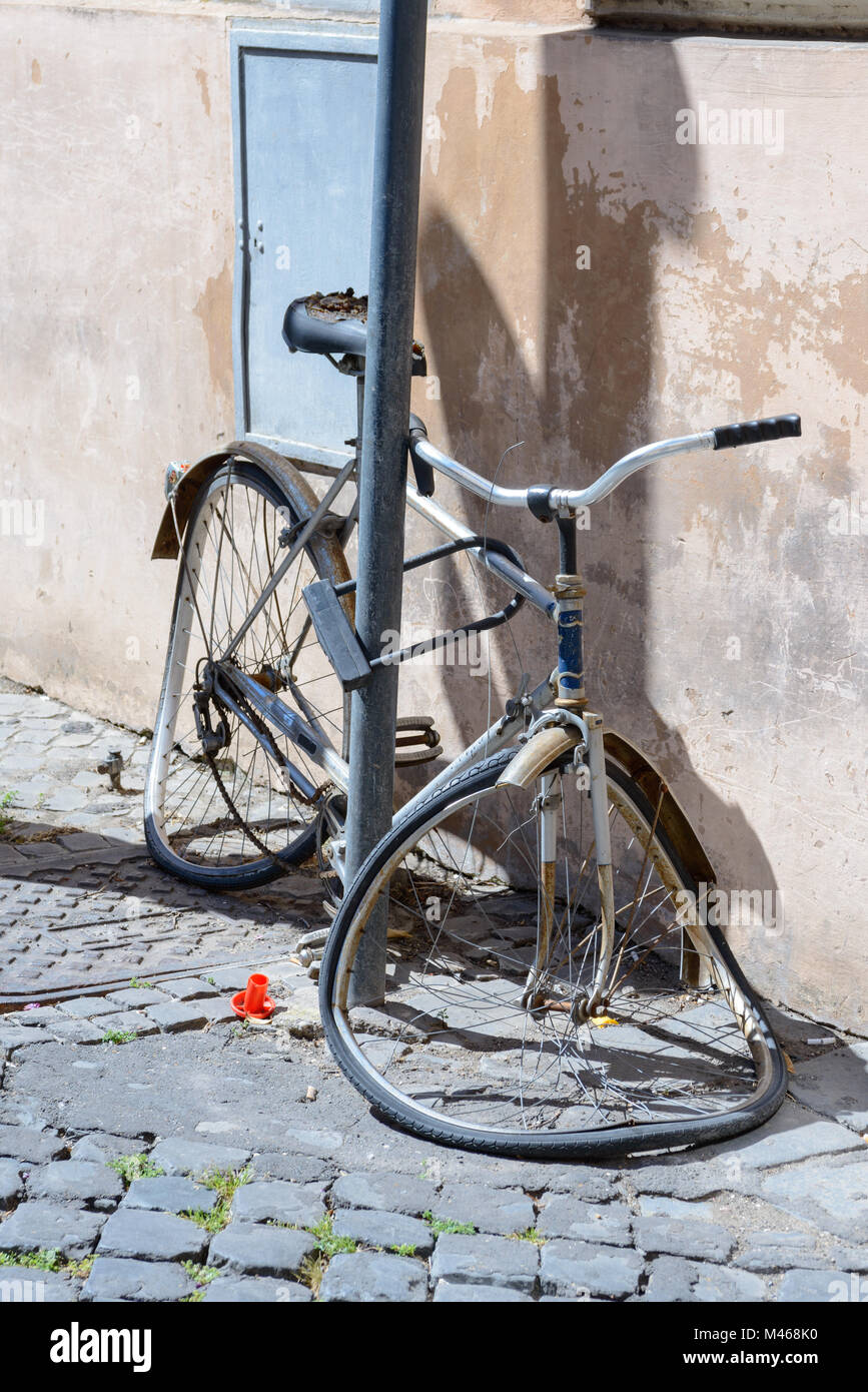 A broken bike tied to a pole in Rome Stock Photo