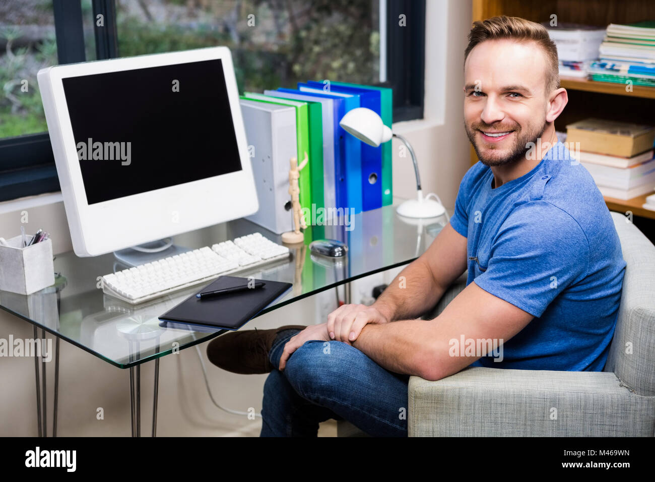 Smiling designer posing while sitting at desk Stock Photo - Alamy