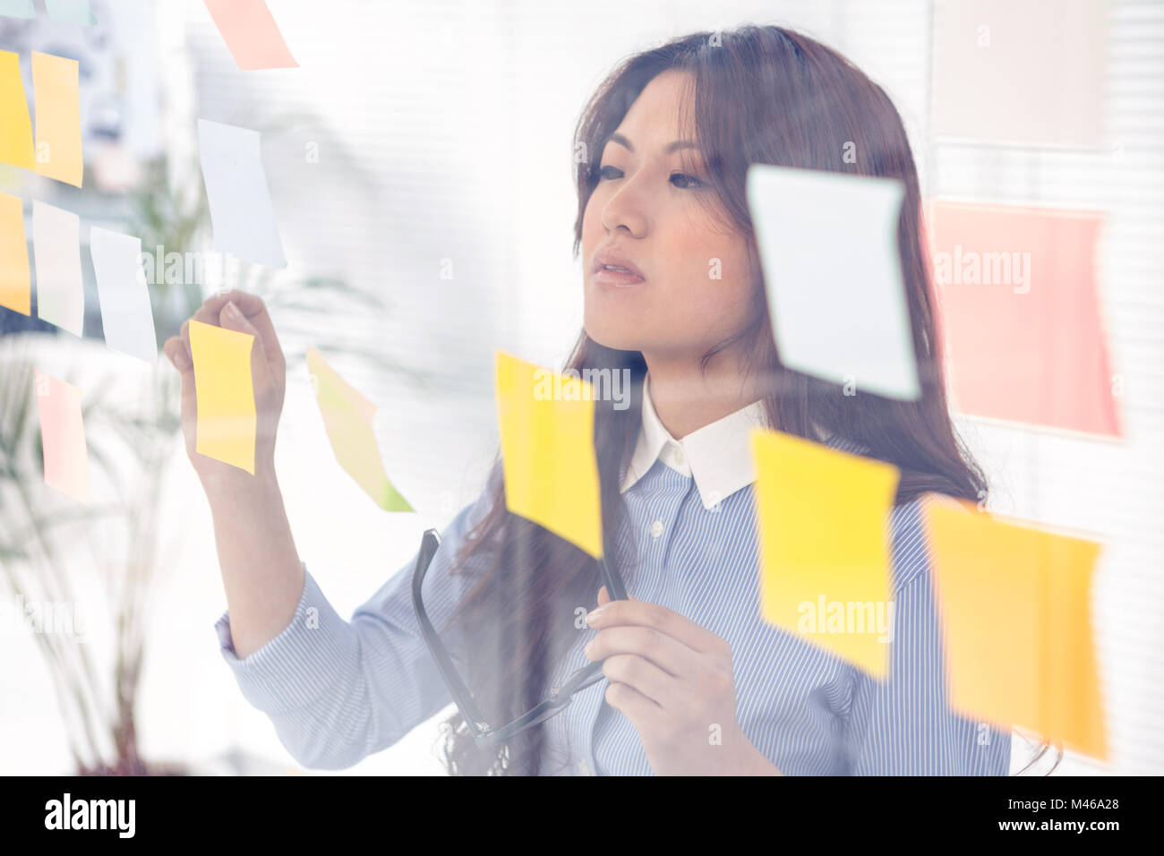 Asian businesswoman using sticky notes on wall Stock Photo - Alamy
