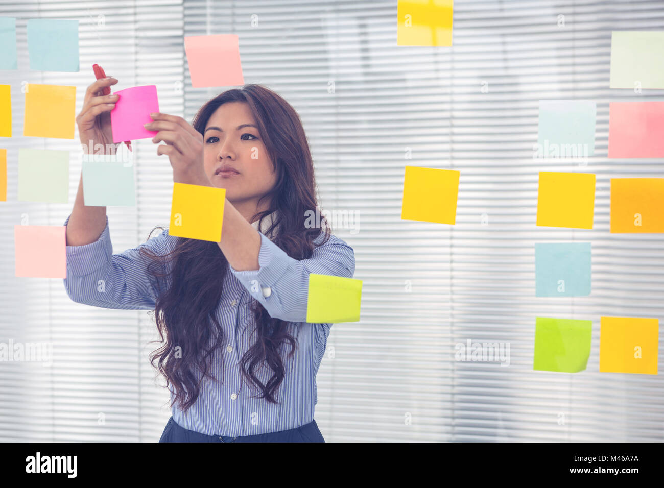 Asian businesswoman using sticky notes on wall Stock Photo - Alamy