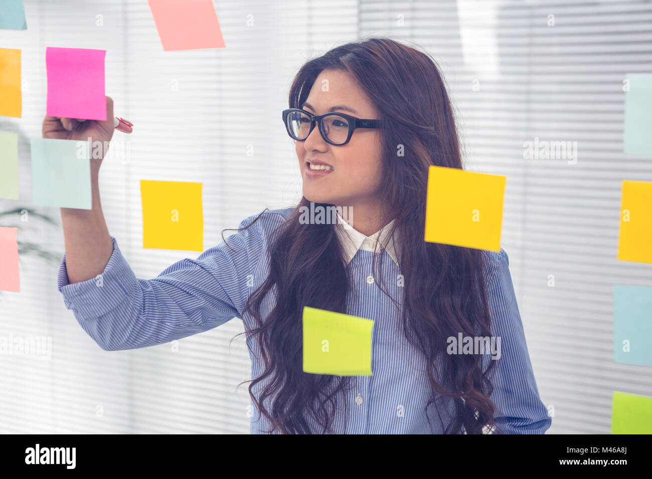 Asian businesswoman using sticky notes on wall Stock Photo - Alamy