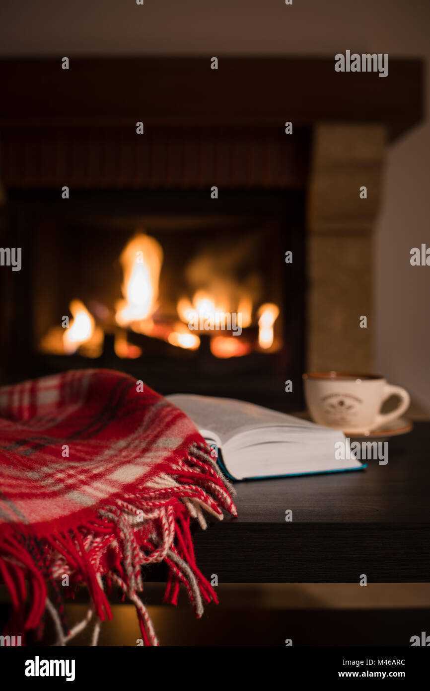 Wool warm blanket or plaid and a book with a cup of tea on the ...