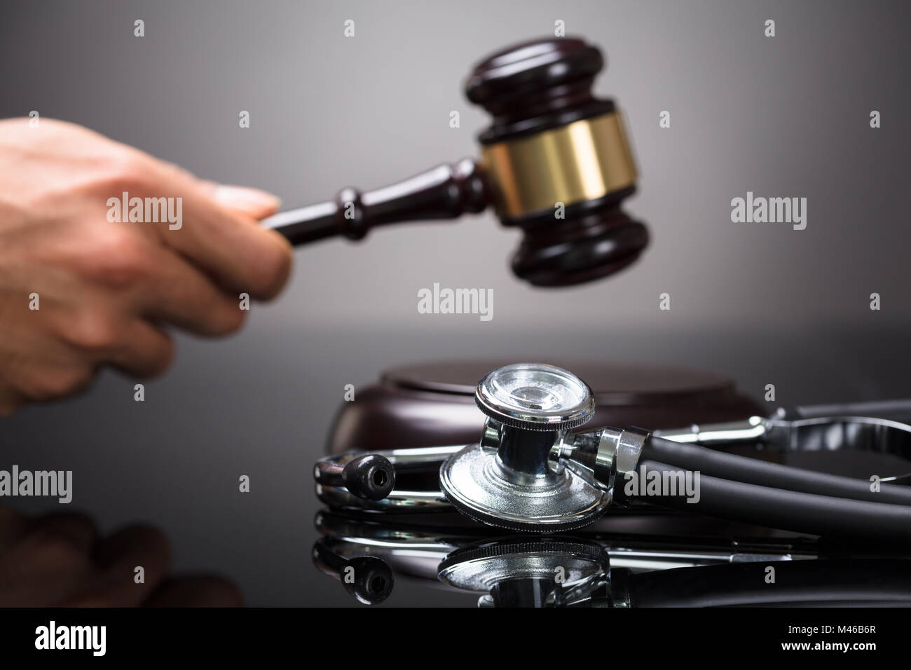 Judge's Hand Striking Gavel With Stethoscope On Desk Stock Photo