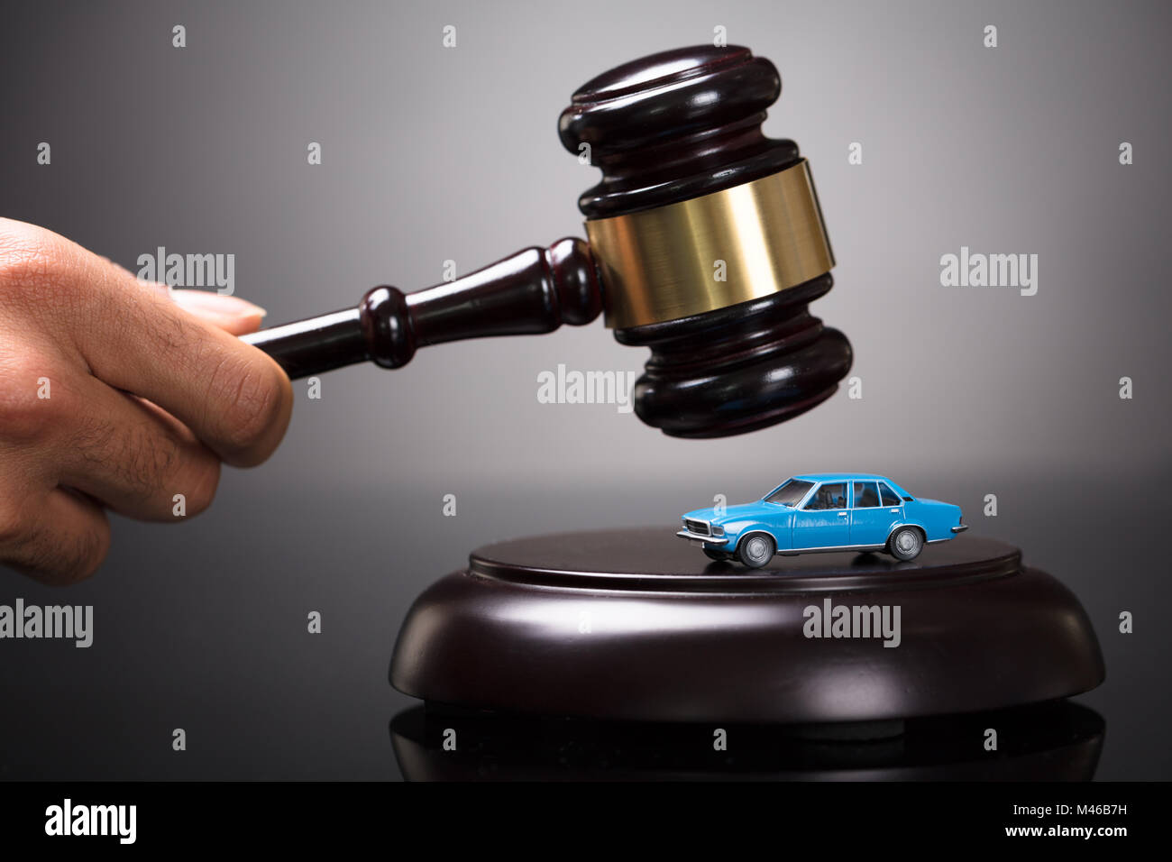 Close-up Of A Judge's Hand Striking Gavel On Small Car In Courtroom Stock Photo