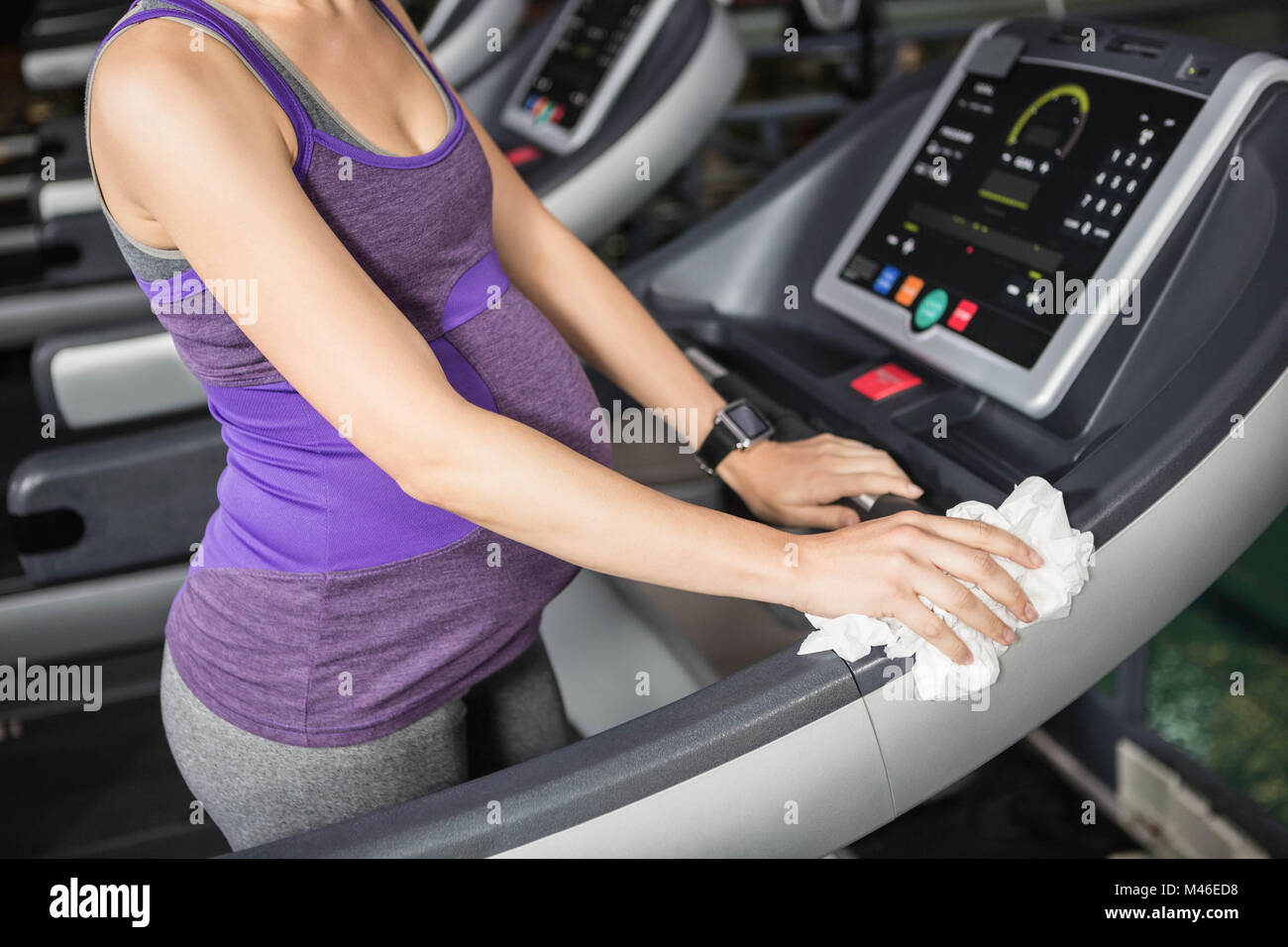 Mid section of pregnant woman cleaning treadmill Stock Photo