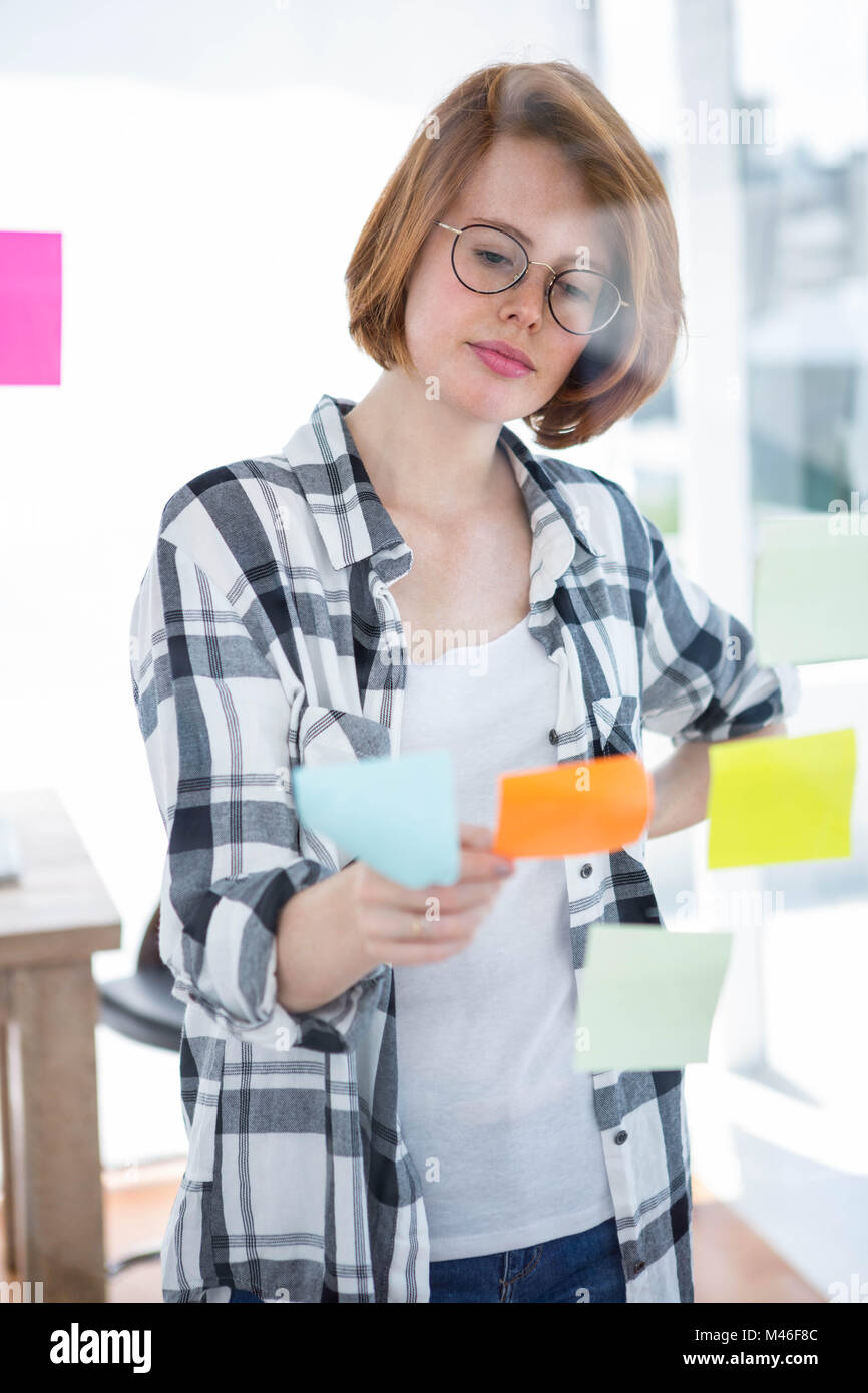 thoughtful hipster woman reading some post it notes Stock Photo