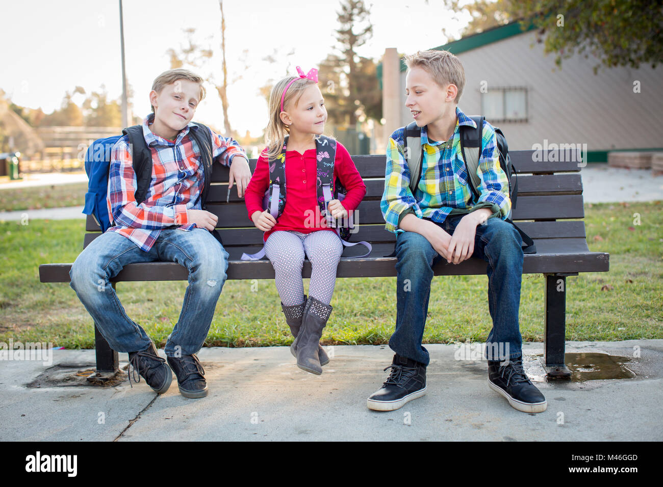 Young school kids sitting on bench Stock Photo Alamy