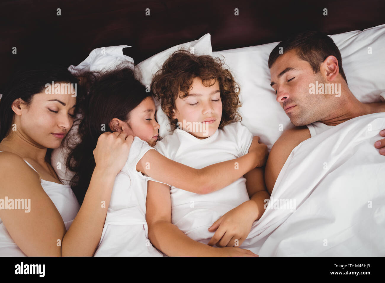 High angle view of children sleeping with parents on bed Stock Photo
