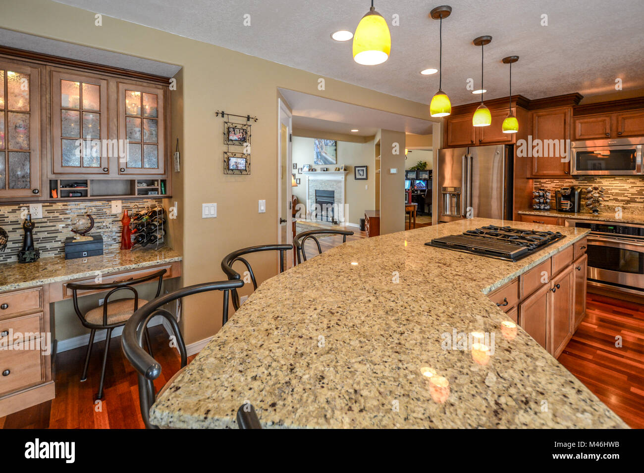 An upscale kitchen with granite slab countertops, hardwood flooring, stainless appliances and extra large center island. Stock Photo