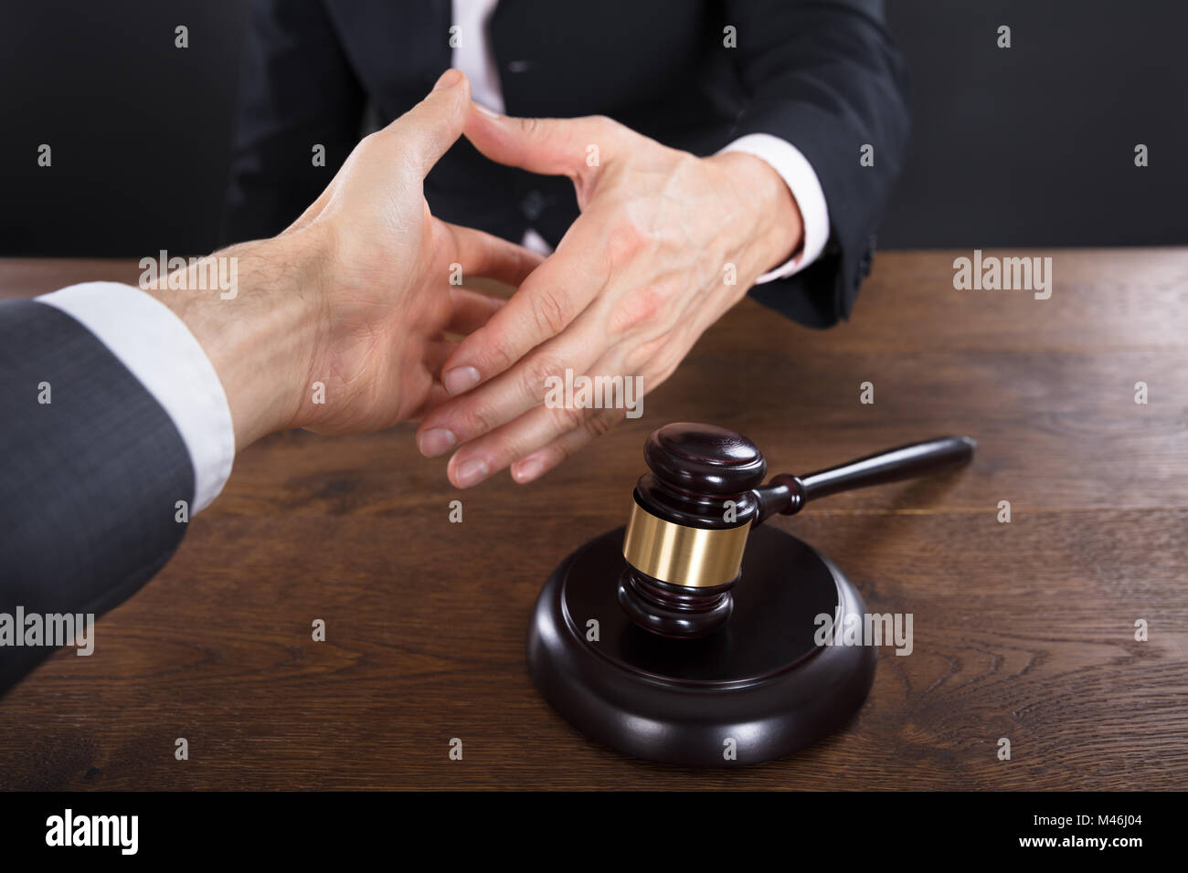 Client And Judge Shaking Hands With Each Other Near Gavel On Wooden