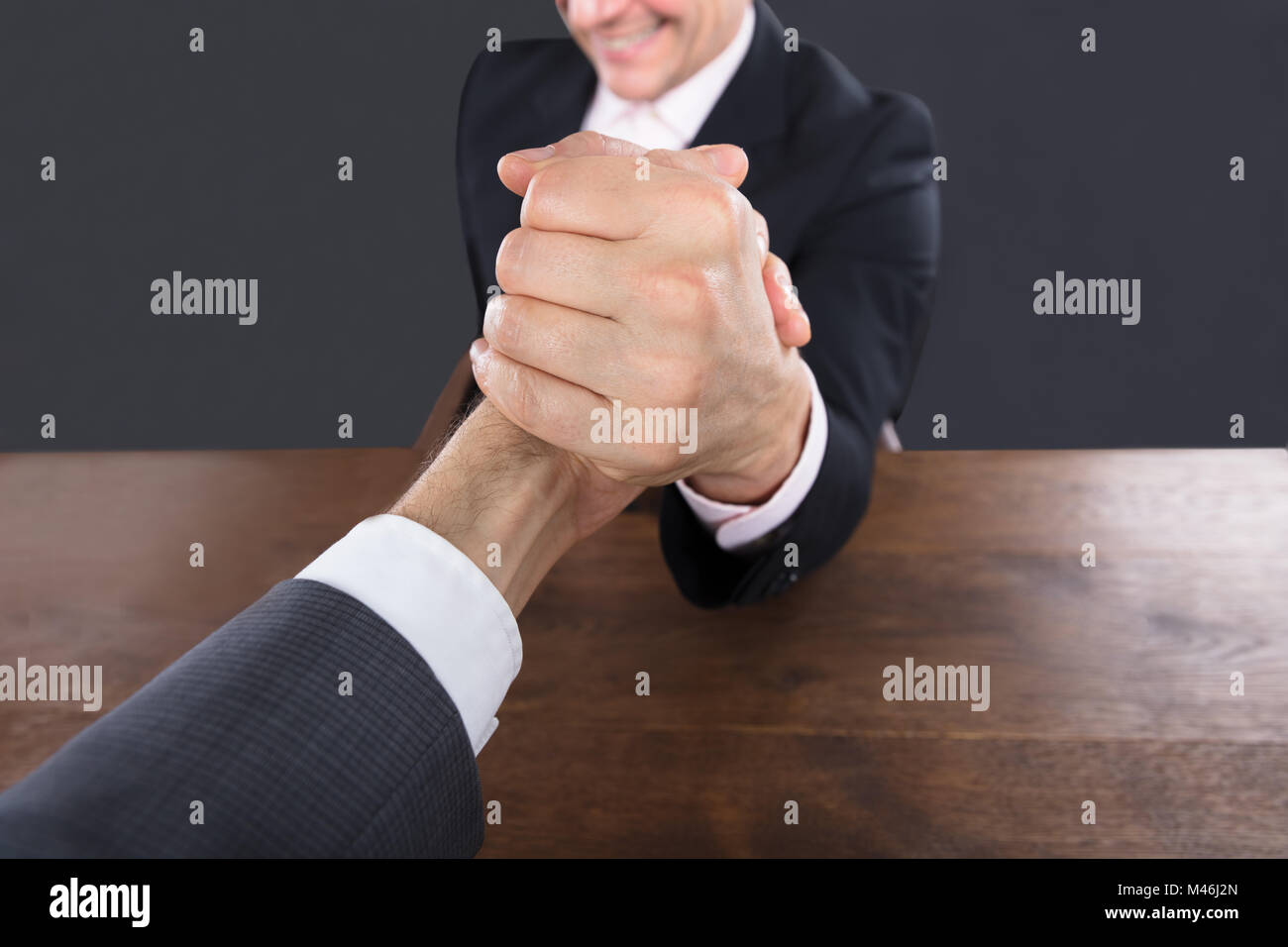 Close-up Of A Two Businessman Competing In Arm Wrestling On Wooden Desk Stock Photo