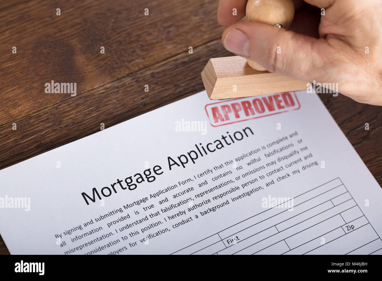 High Angle View Of An Approved Stamp On Mortgage Application Form At Wooden Desk Stock Photo