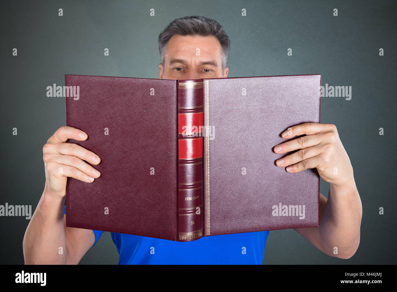 Close-up Of A Man Reading A Book On Gray Background Stock Photo
