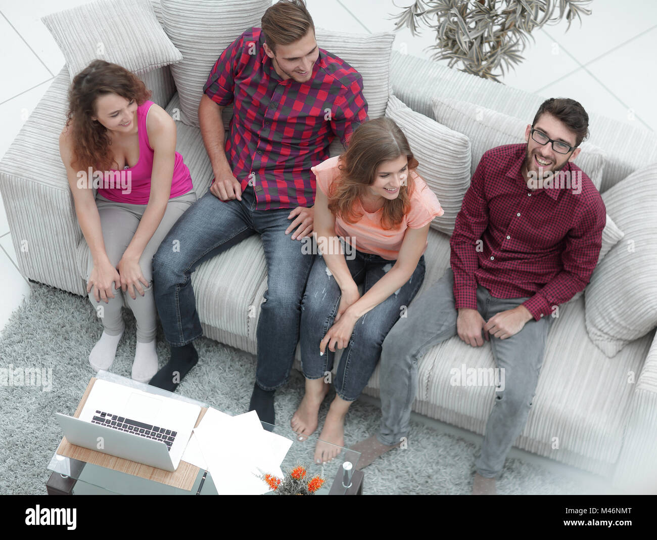 triumphant group of friends laughing while sitting on the couch in the ...