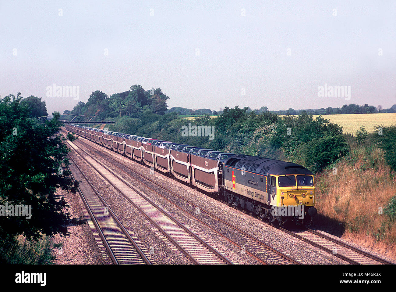 A class 47 diesel locomotive number 47241 working a loaded car train at Shottesbrooke in Berkshire on the 20th July 1996. Stock Photo