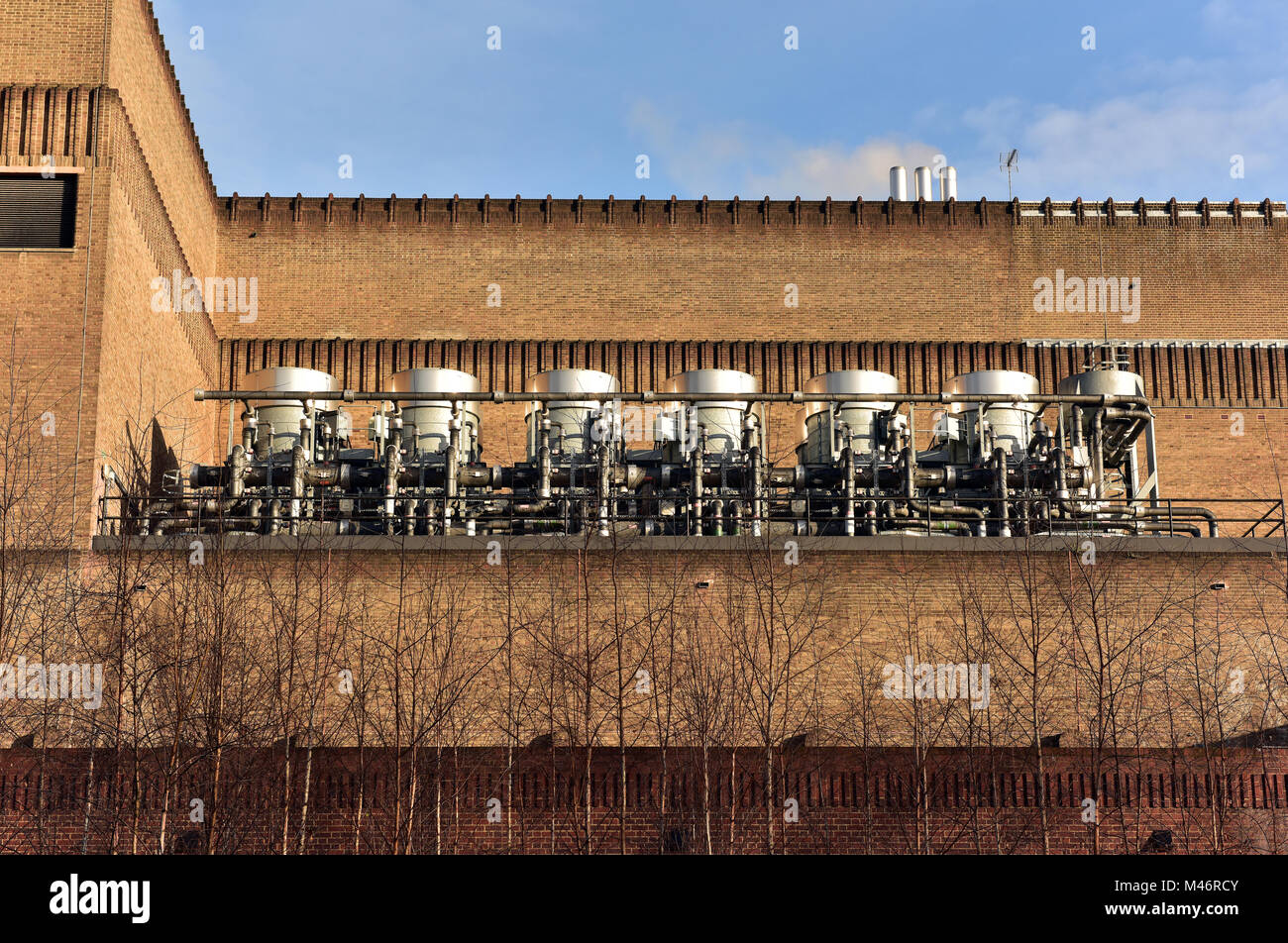 Electrical power generating or generation breakers and transformers outside of a large industrial building in a row or line producing electricity. Stock Photo