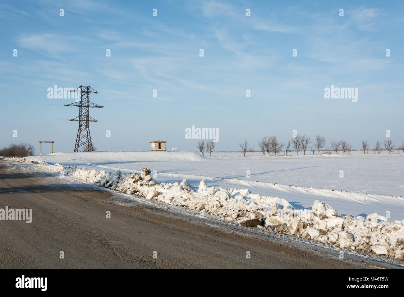 Electrical power line pillar on snow in front of blue sky and clouds ...