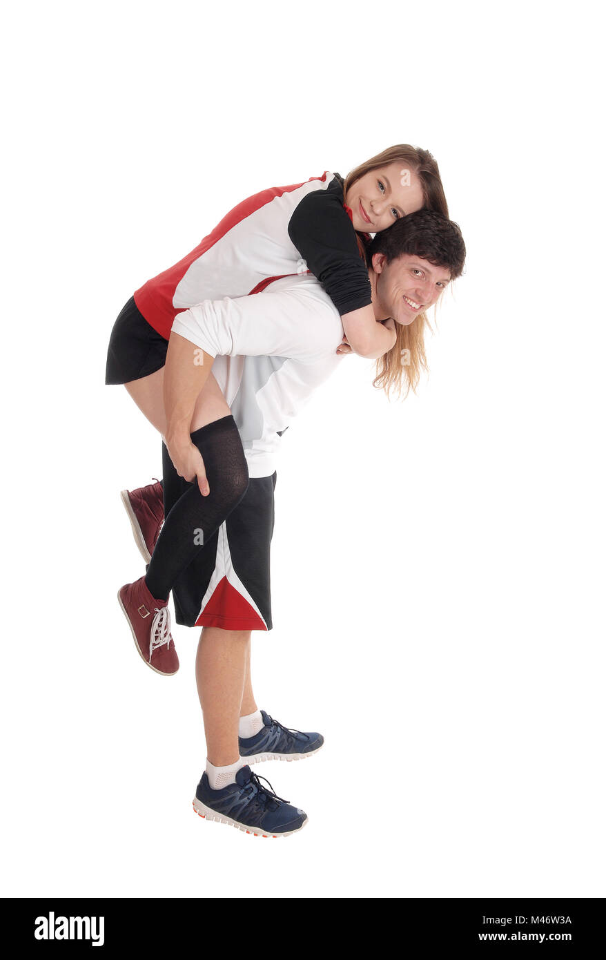 A lovely young couple standing in exercise outfits the man piggyback his girlfriend, isolated for white background Stock Photo