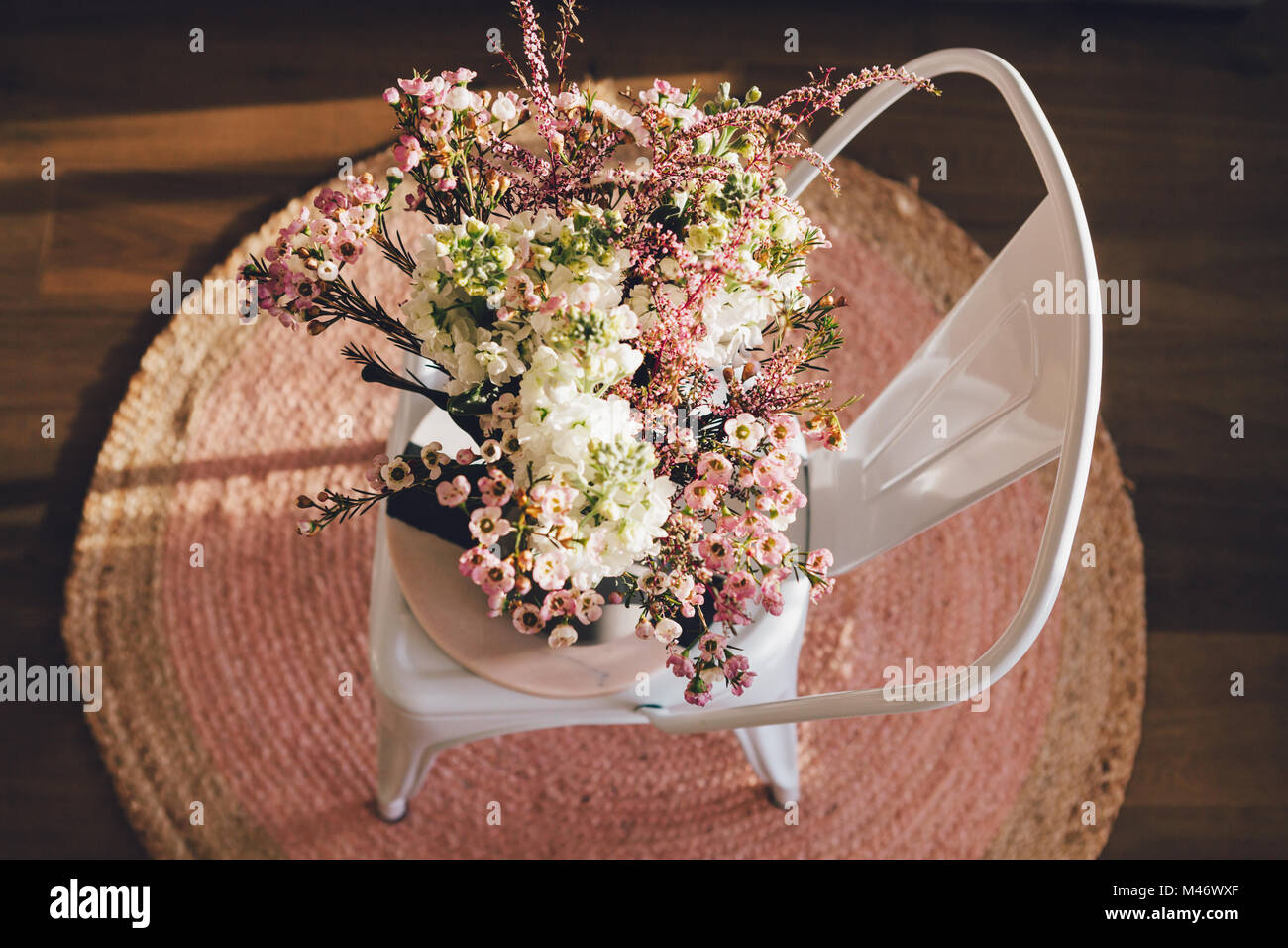 Stunning fresh flowers on a chair and pink rug from overhead Stock Photo