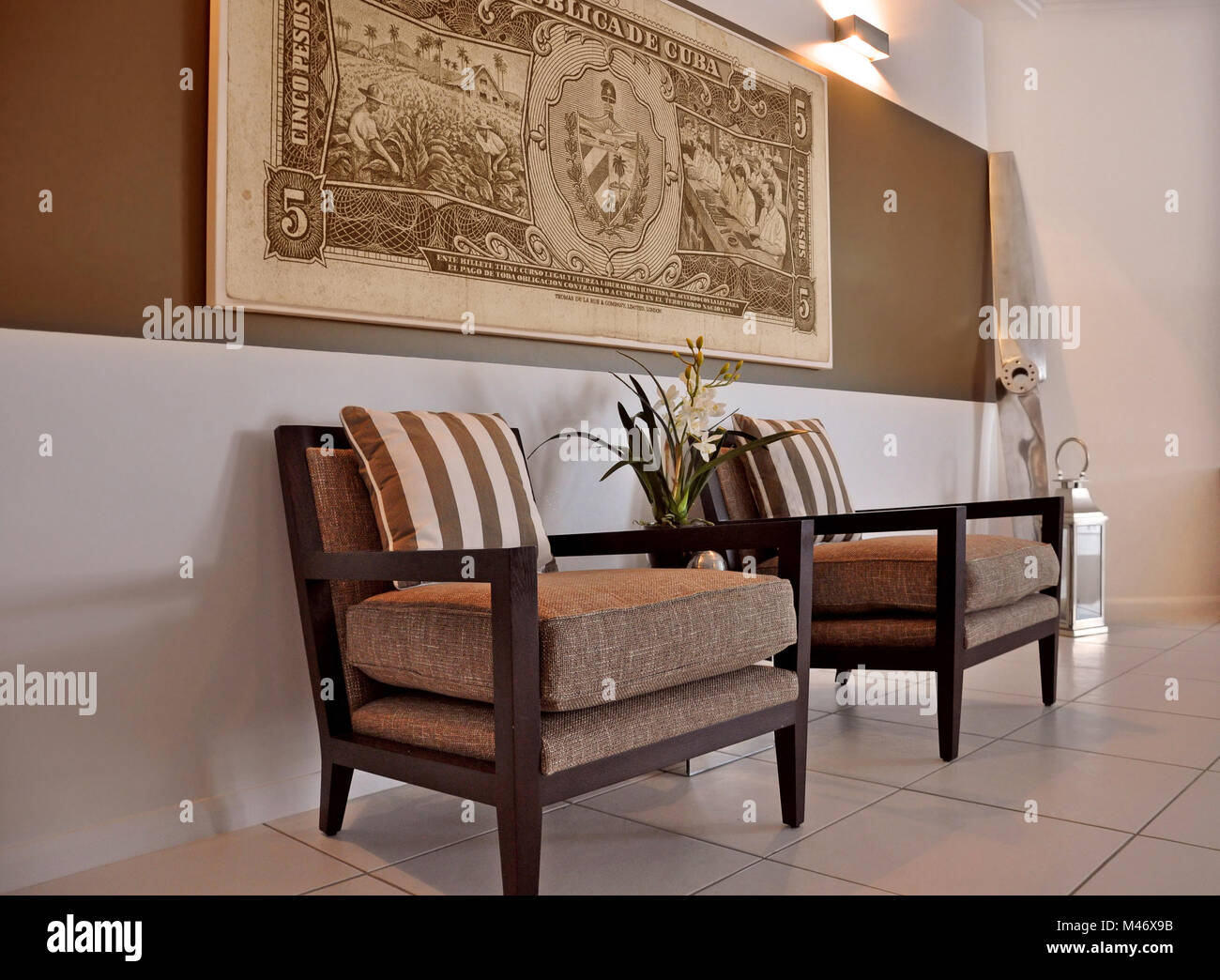 Stylish occasional chairs under a striped feature wall with a cuban currency note enlarged onto a canvas Stock Photo