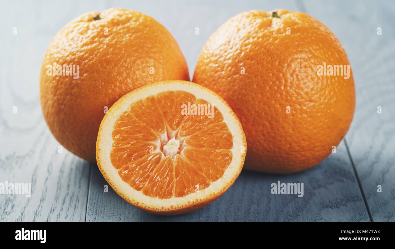 ripe oranges with half sliced on blue wood table Stock Photo