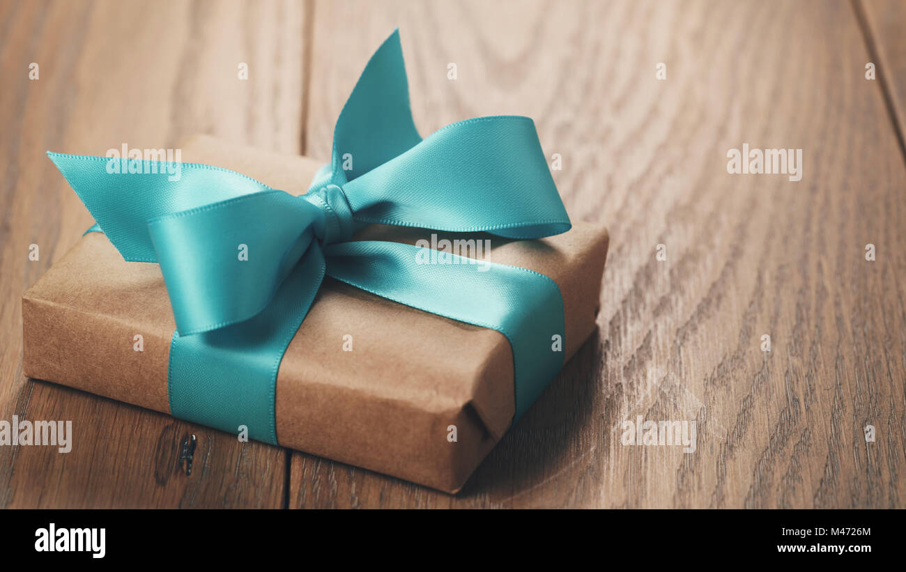 rustic craft paper gift box with blue ribbon bow on wood table Stock Photo