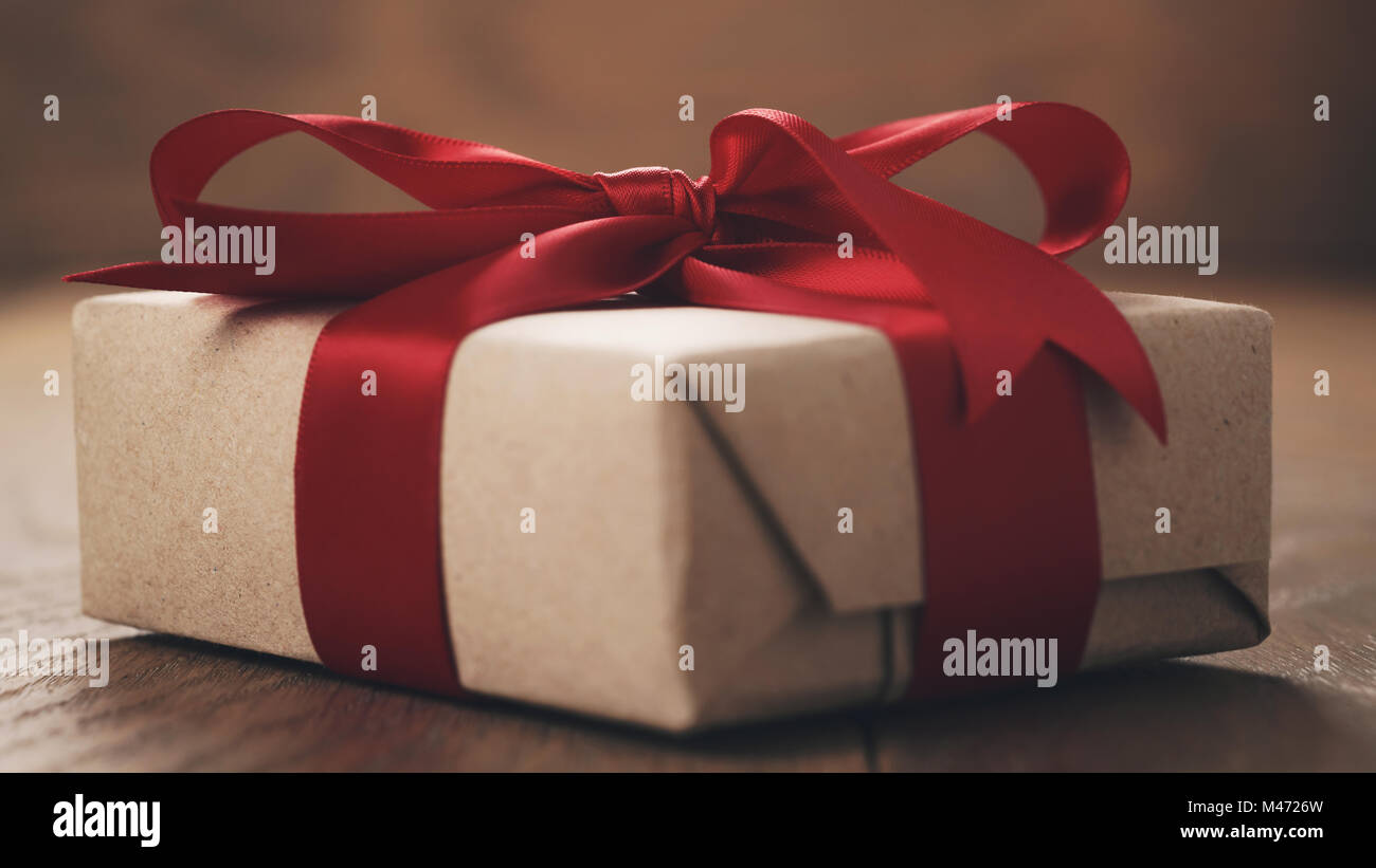 rustic craft paper gift box with red ribbon bow on wood table Stock ...