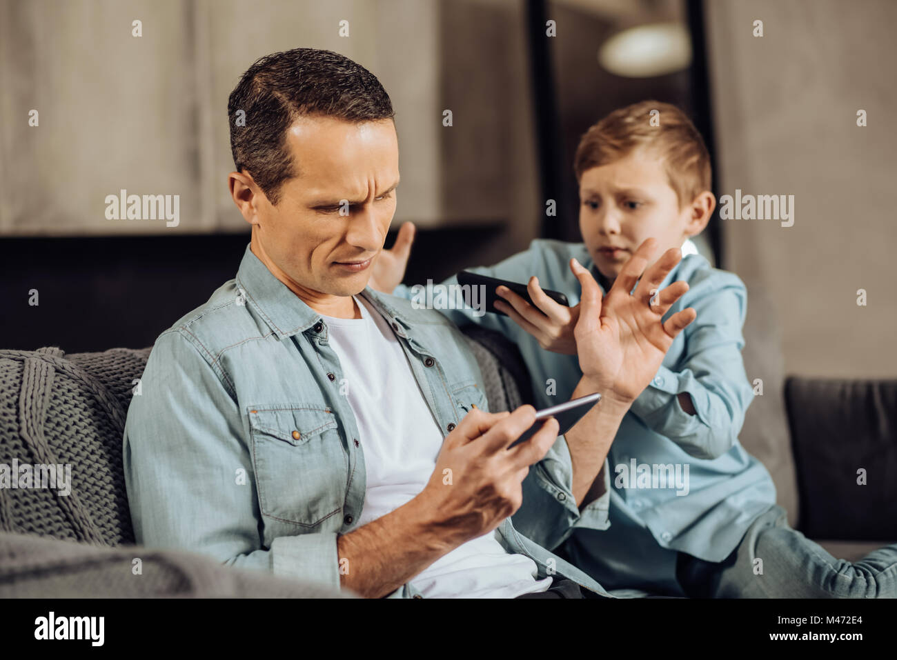 Busy father brushing away his son asking for attention Stock Photo