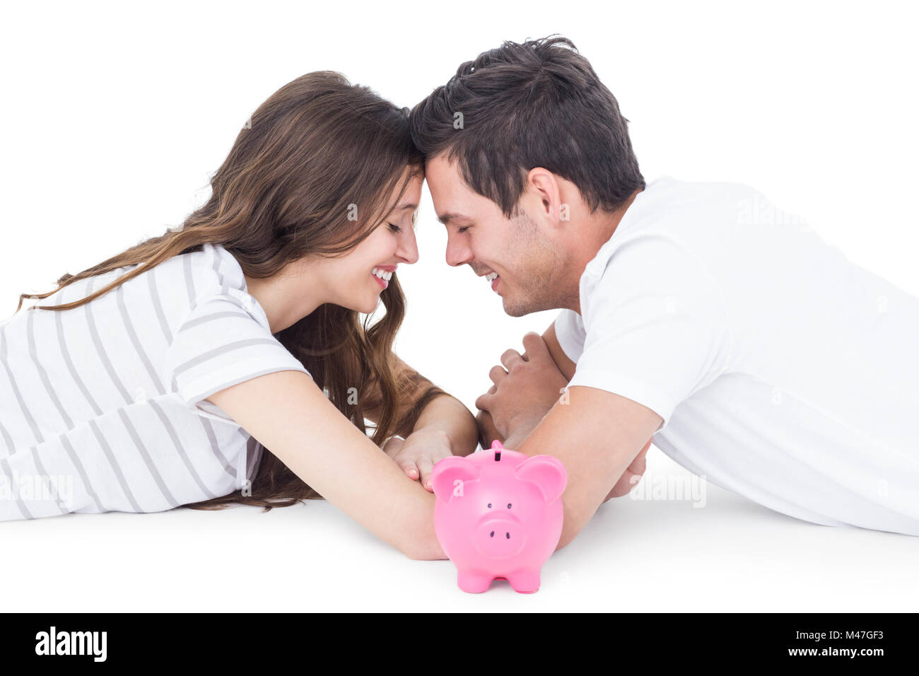 Happy couple lying on the floor with piggy bank Stock Photo - Alamy