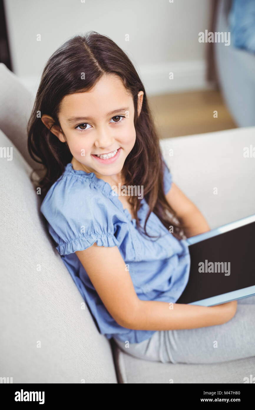 Girl using digital tablet while sitting on sofa at home Stock Photo - Alamy