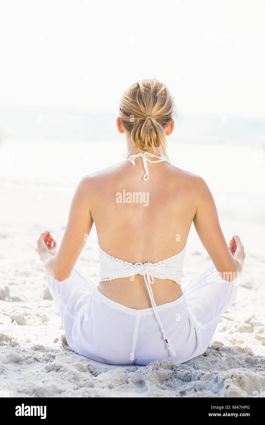 Rear view of woman performing yoga on the beach Stock Photo - Alamy
