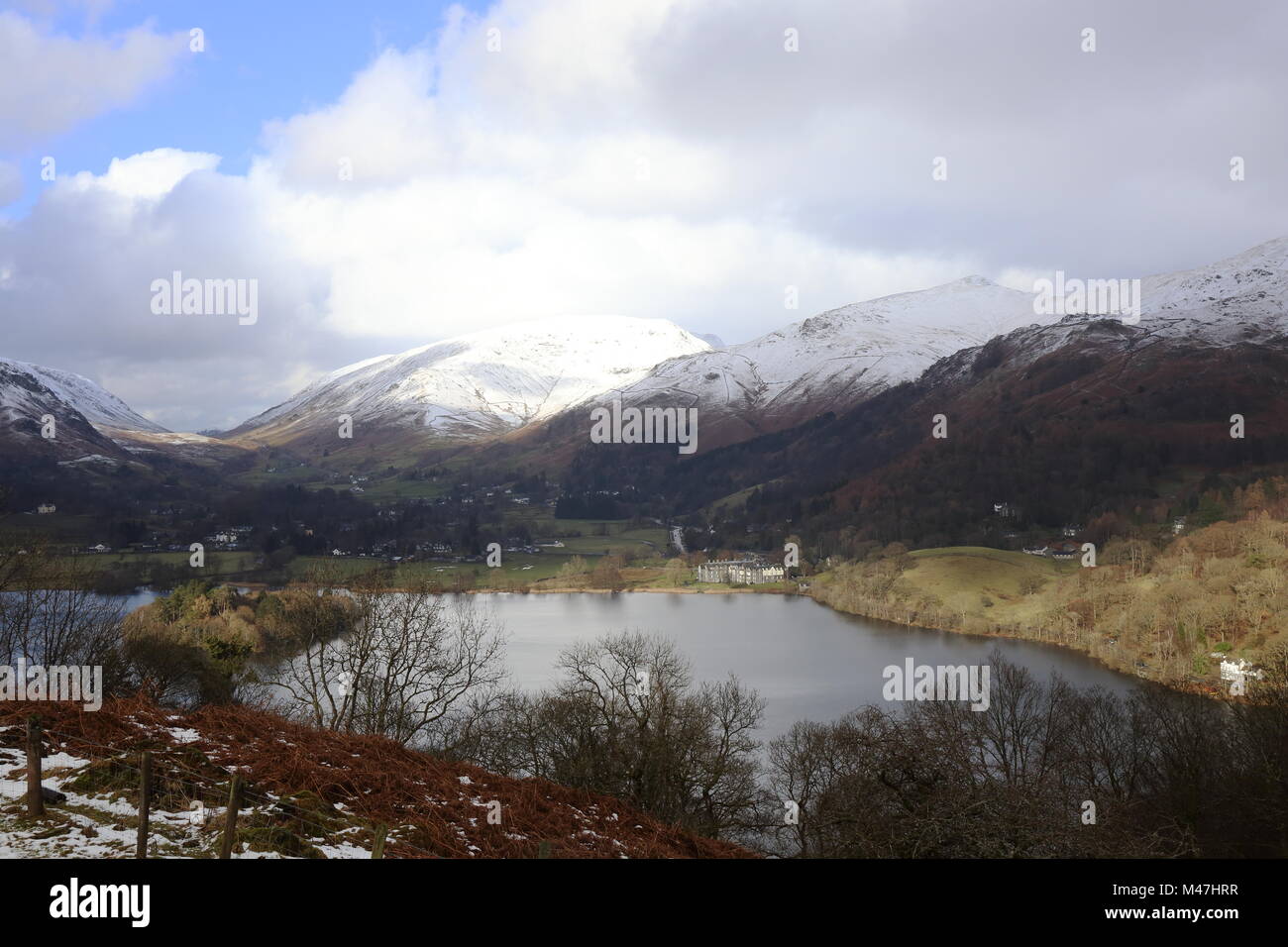 Grasmere, Cumbria, in mid winter, bright sunlight reflects off the snow covered Helvelyn range. Stock Photo